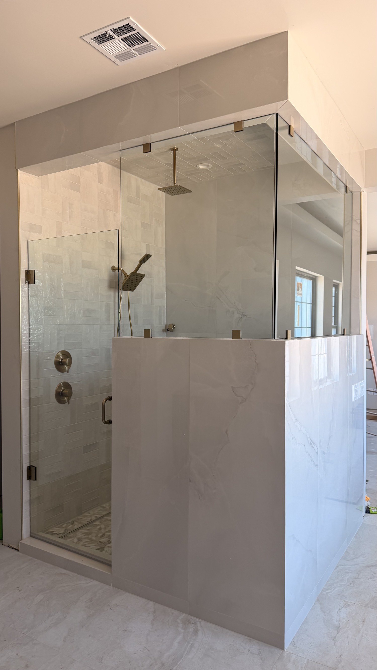 Walk-in shower with large marble walls, a glass enclosure, and a rain shower