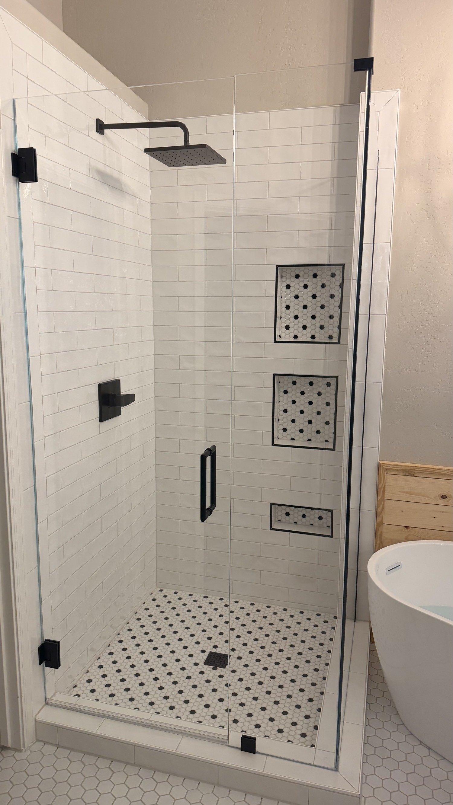 White subway tile shower with a hexagon floor and three niches