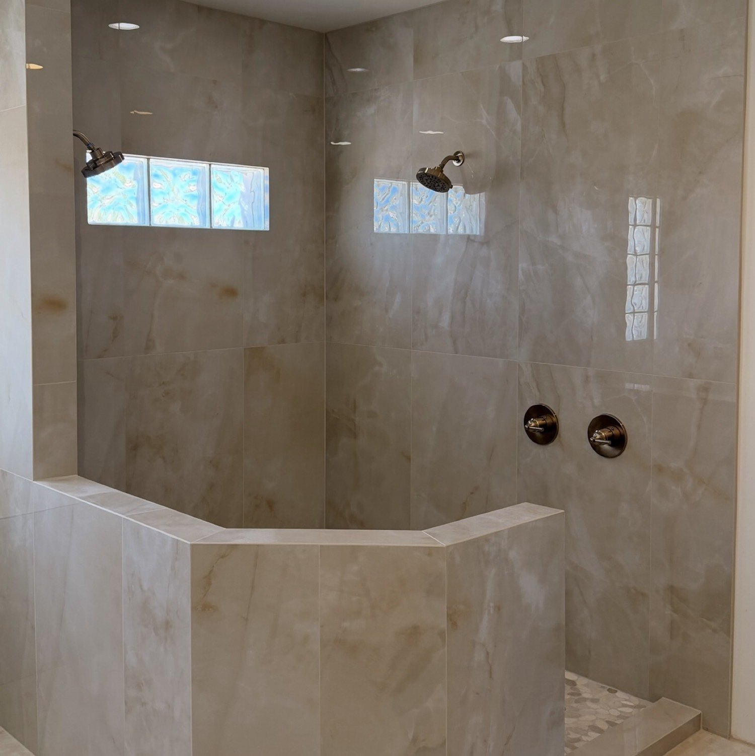 Large-format stone shower with glass-block windows and a tiled half wall